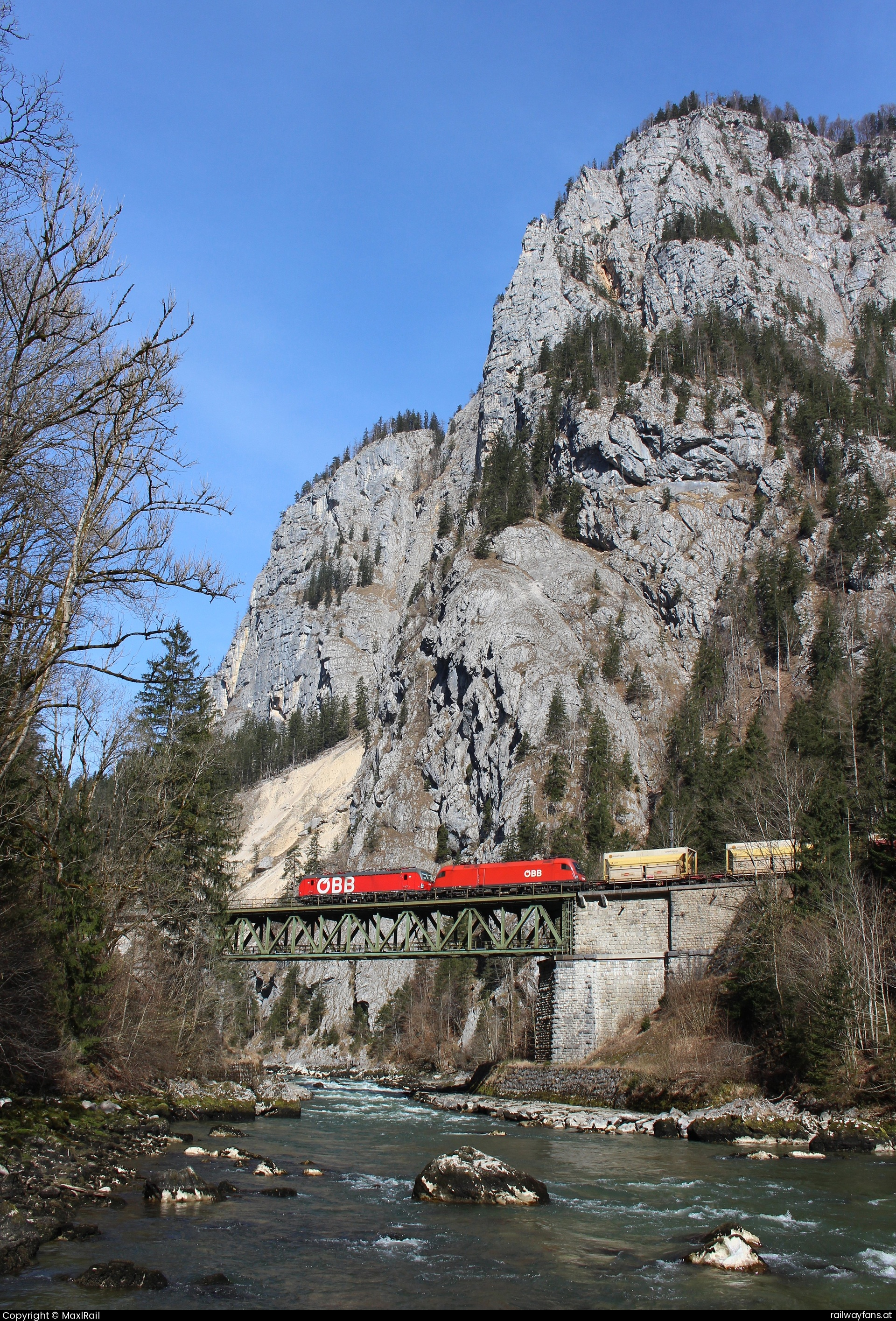 ÖBB 1293 098 in Admont - Von Eisenerz kommend fahren am 11.3.2025 die 1293 098 und die 1116 102 mit einem Erzzug Richtung Leoben Donawitz über die imposante Gesäuse Eingang Brücke mit dem 1222m hohen Himbeerstein im Hintergrund.  Gesäusebahn Railwayfans