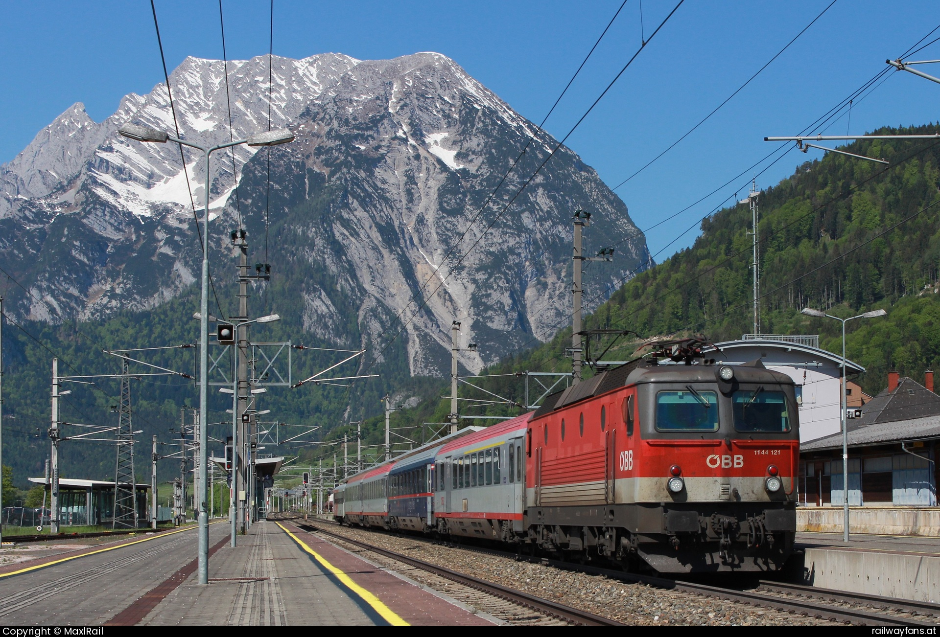 ÖBB 1144 121 in Stainach-Irdning mit dem IC 513 - Ein bekanntes und beliebtes Vormittagsmotiv ist seit jeher der Bahnhof Stainach-Irdning mit dem 2351m hohen Grimming im Hintergrund.
Seit der Modernisierung des Bahnhofs mit modernen Bahnsteigen leider nicht mehr ganz so schön allerdings dennoch fotogen, so wie hier am 2.5.2025 mit der 1144 121 und dem IC513 